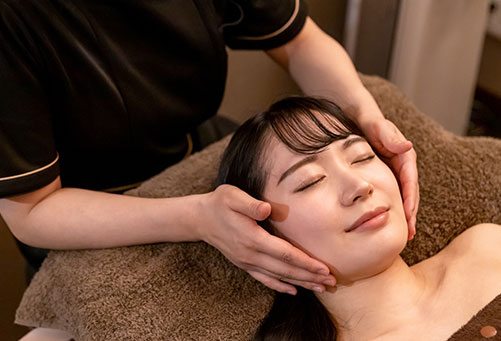 顔マッサージを受けるリラックスした女性
