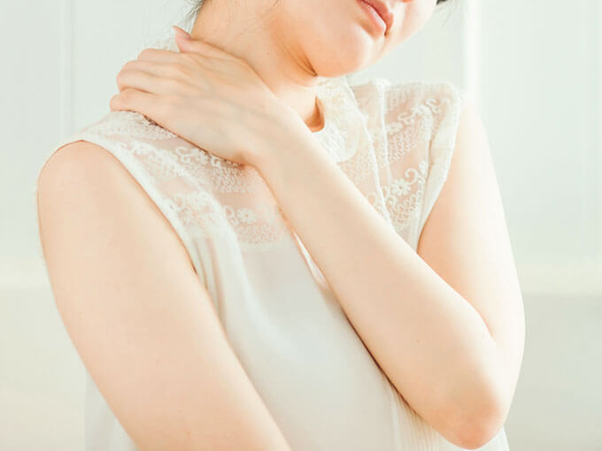 首を手で支える女性の後ろ姿